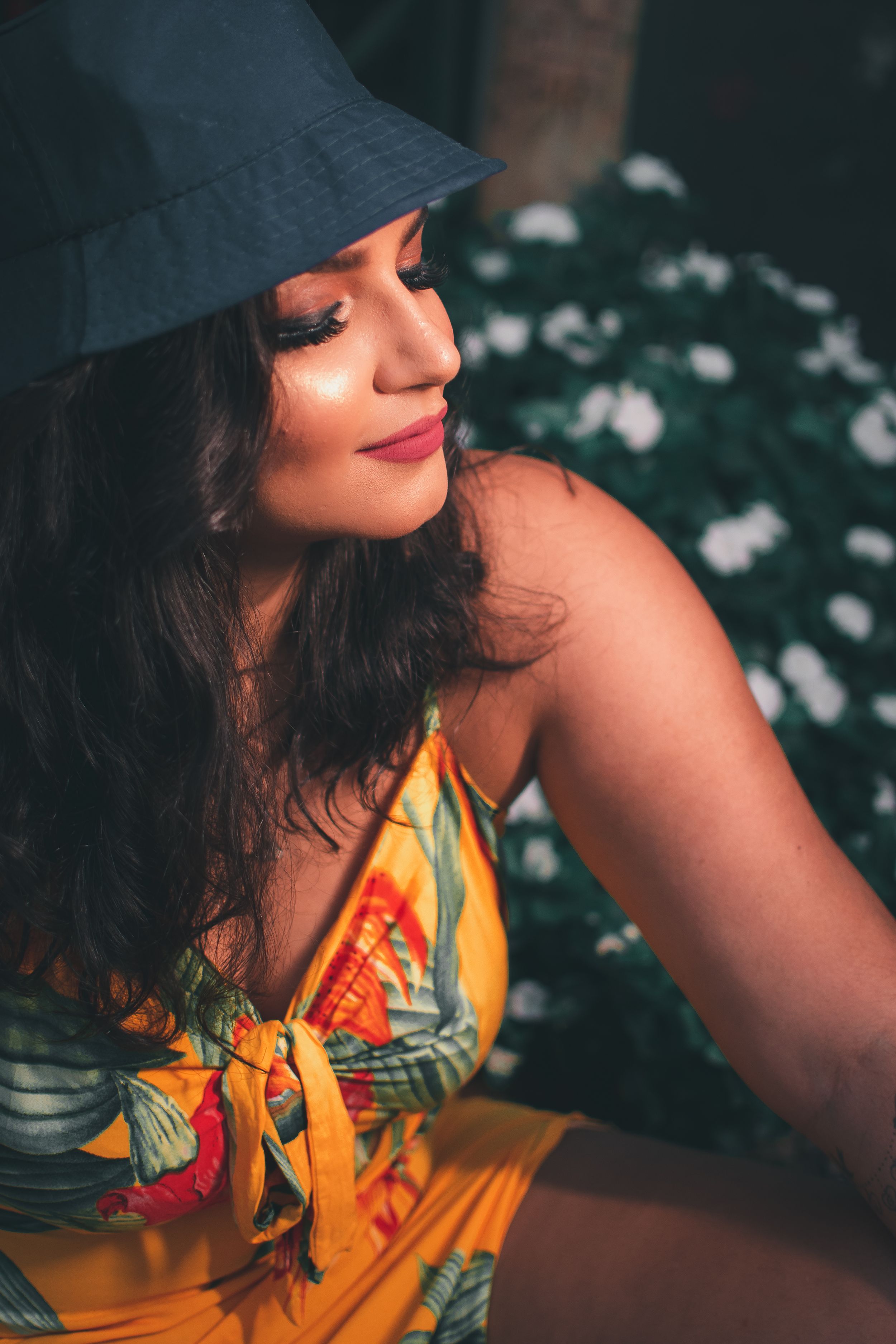 Portrait series showing a yellow floral dress and black hat in warm sunlight.