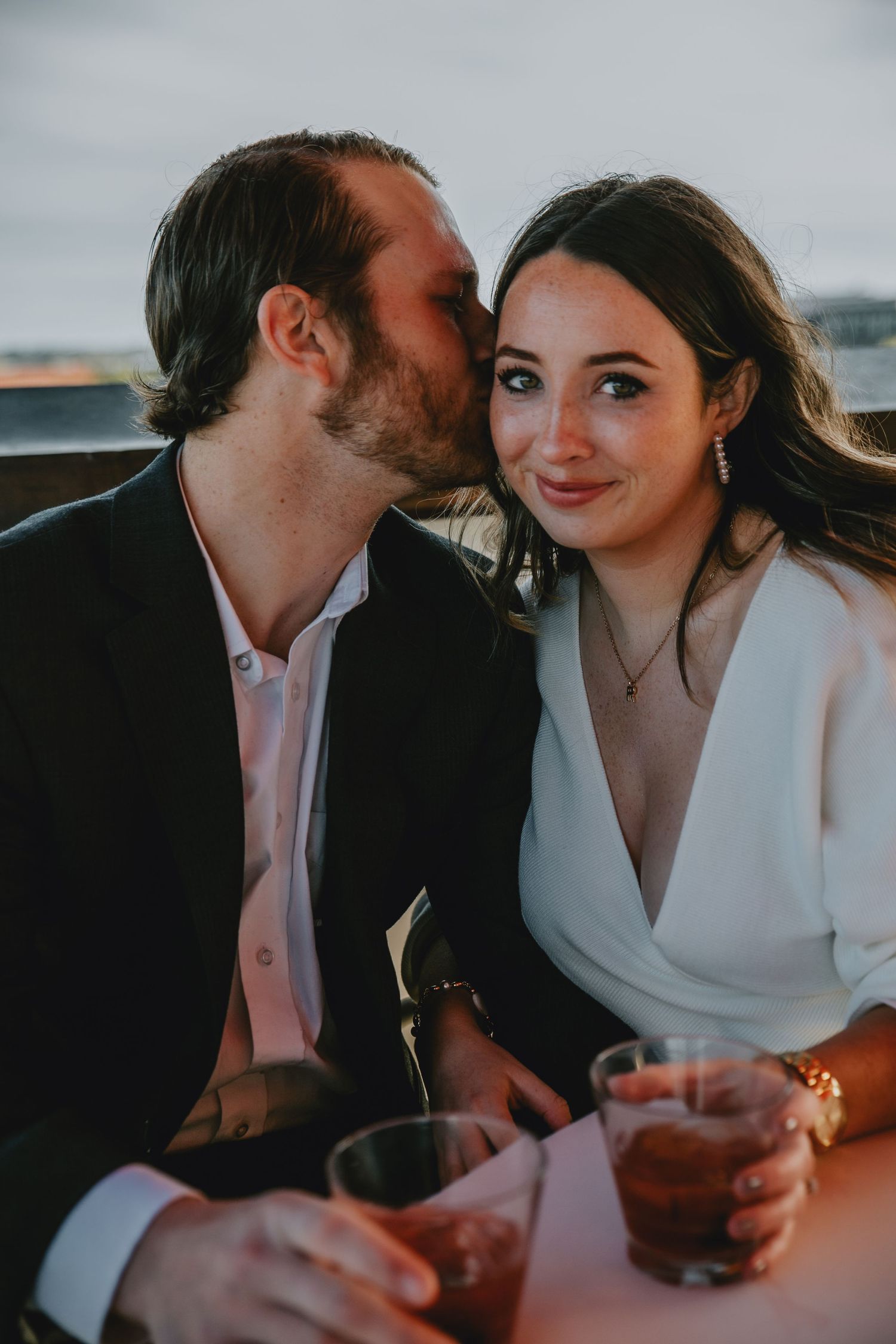 A man gives a kiss to a woman while sharing drinks