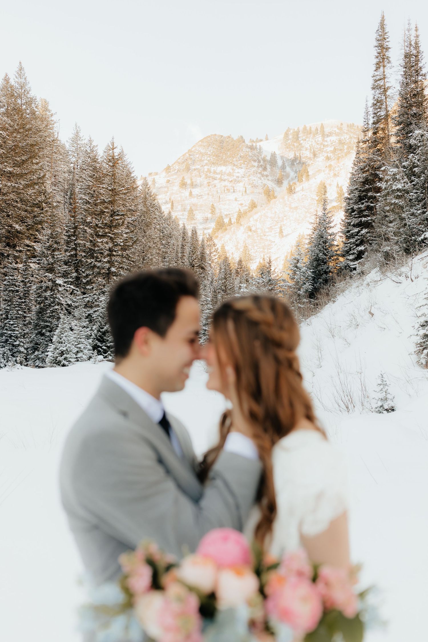 Blurry bride and groom in crisp winter mountain with pine trees