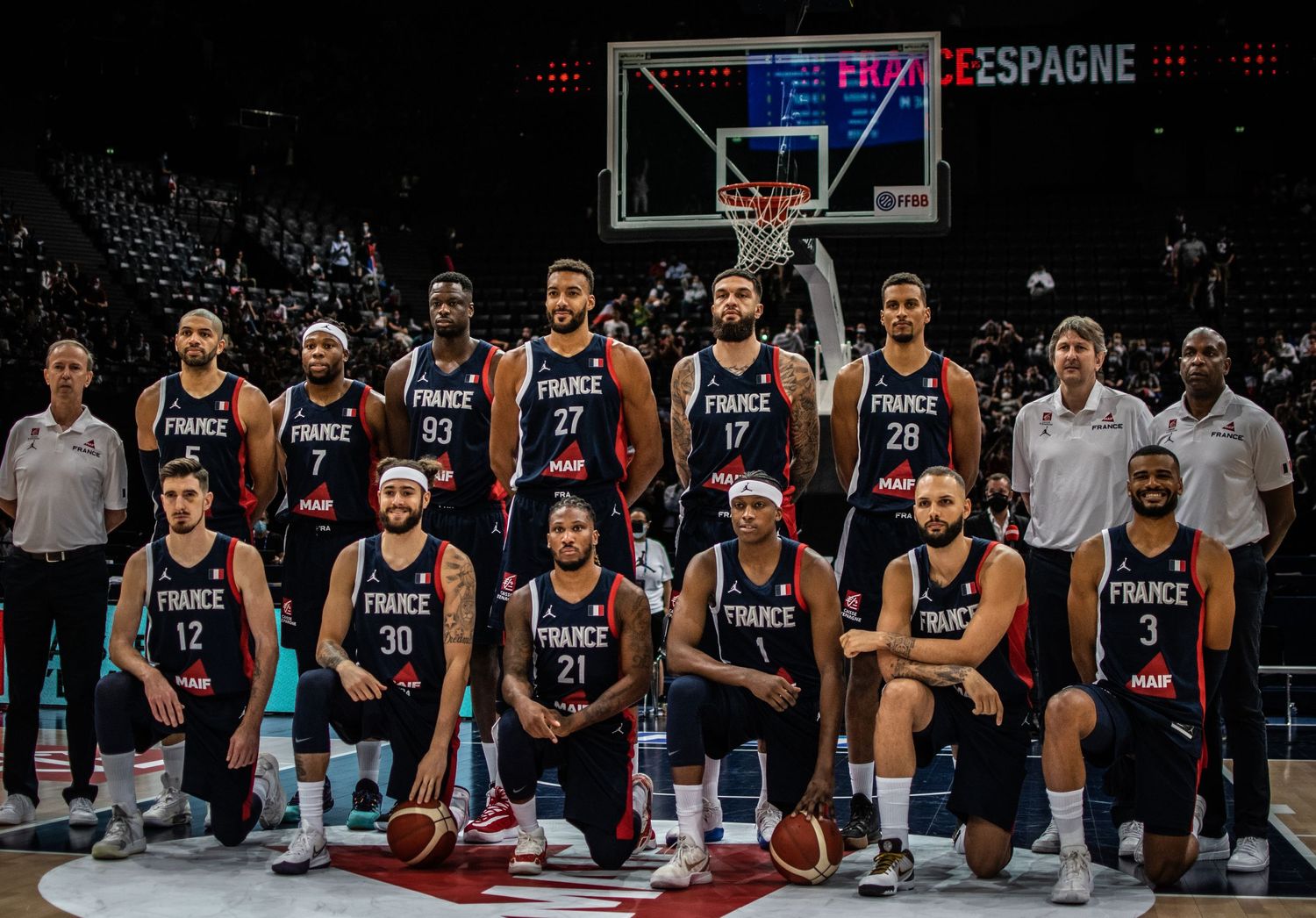 French national basketball team poses for group photo in navy uniforms.