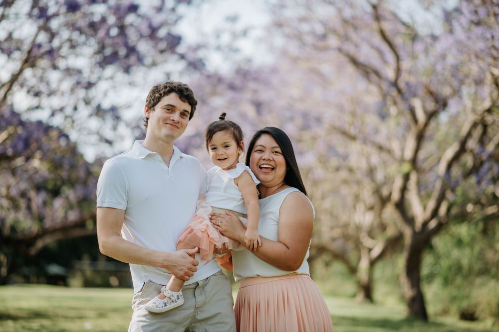 A family stands together under blooming cherry blossom trees in springtime.