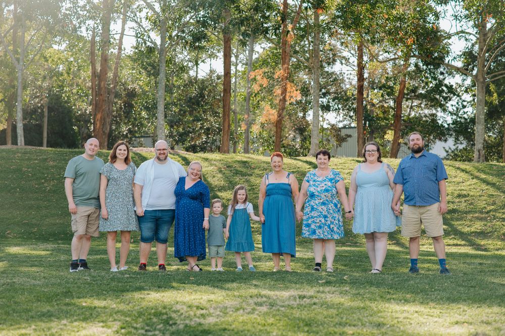 Coordinated family photo with matching outfits standing in wooded park setting.