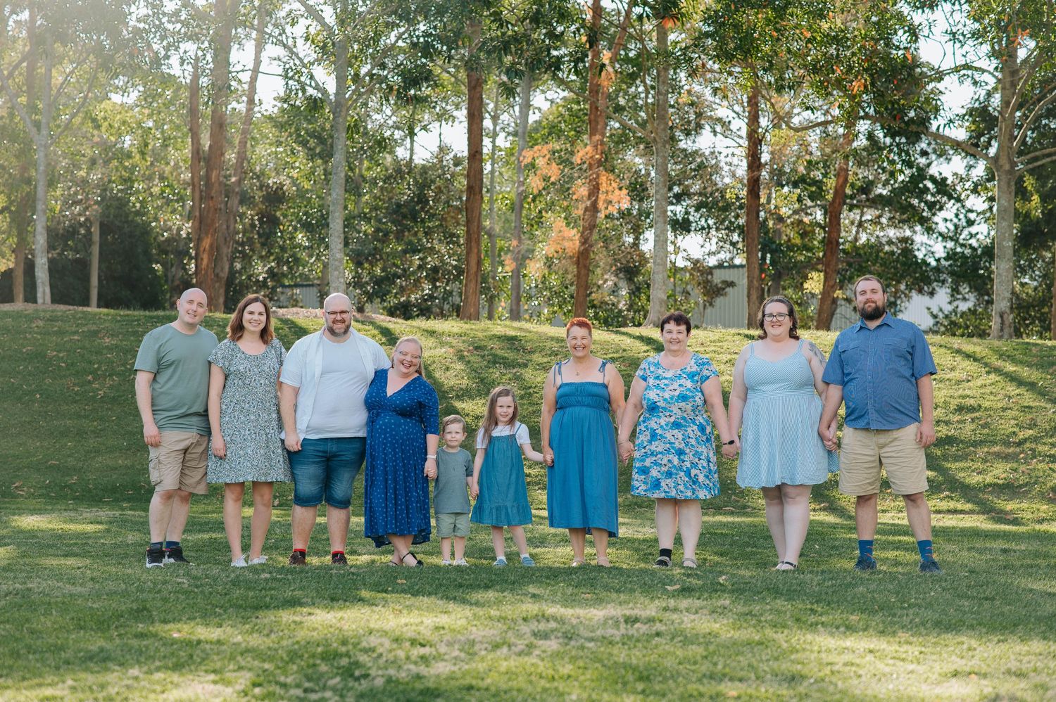 Coordinated family photo with matching outfits standing in wooded park setting.