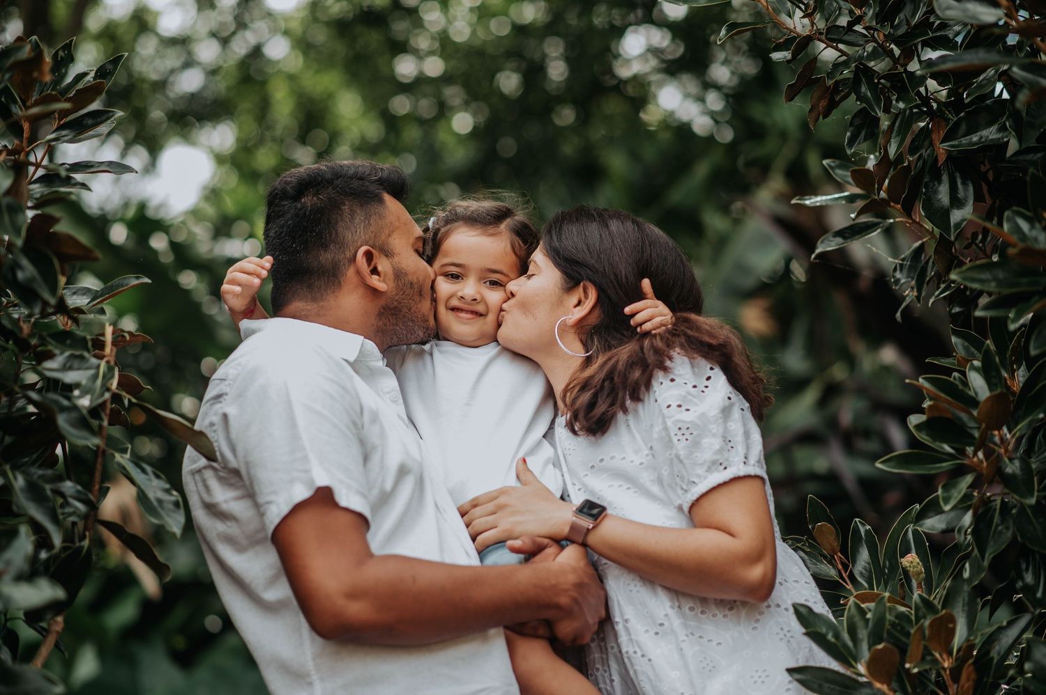 A loving family moment captured in an outdoor garden setting with white attire.