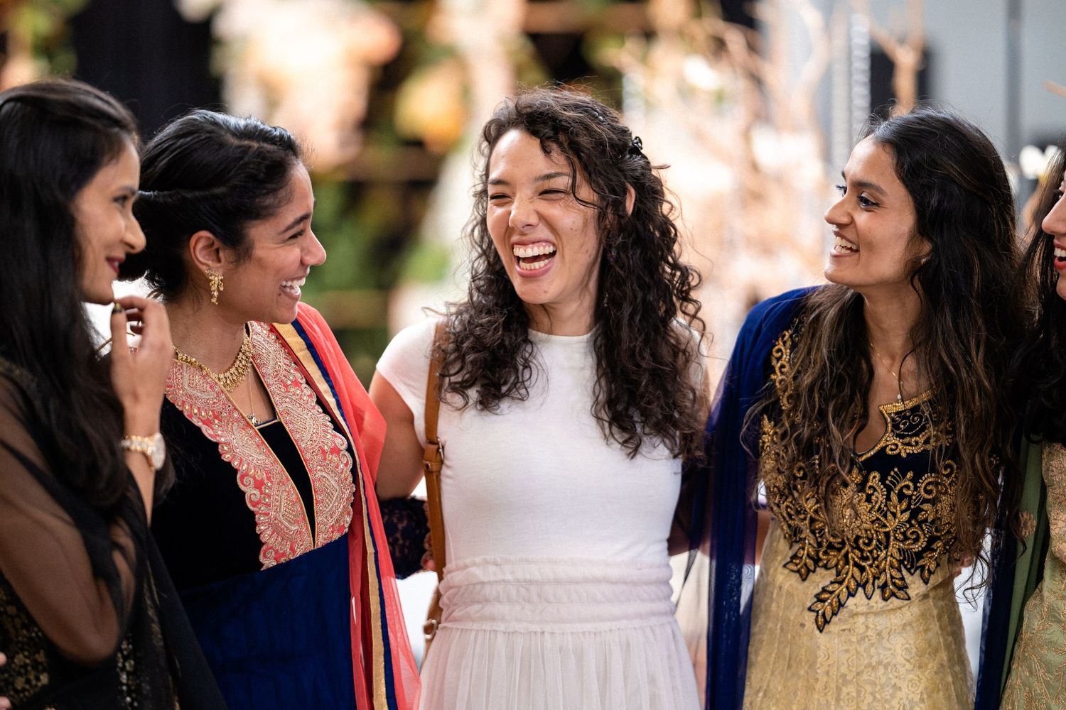 wedding guests adorned in vibrant South Asian attire, sharing joyful laughter, a celebration of unity and rich cultural
