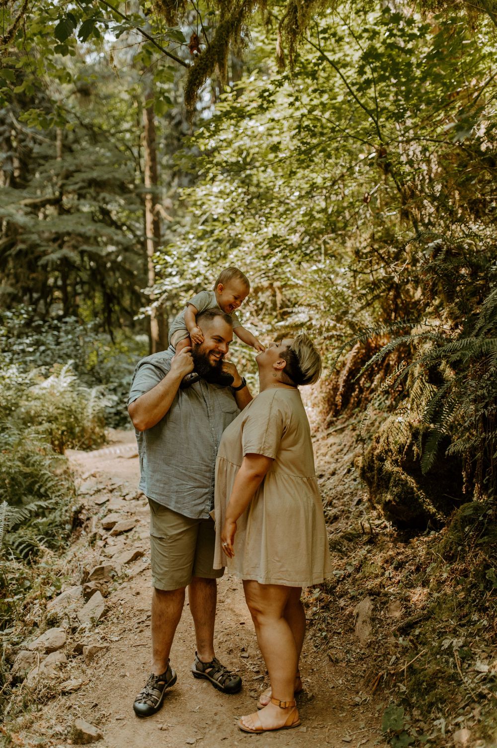 A family shares a tender moment while hiking through a forest trail.