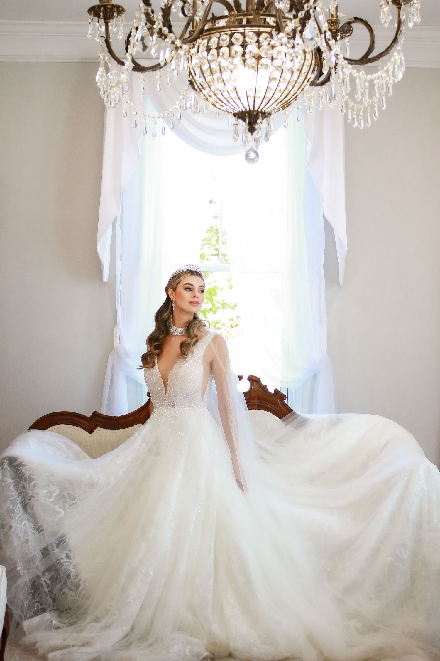 Romantic bridal photos featuring a flowing lace wedding gown under crystal chandeliers.