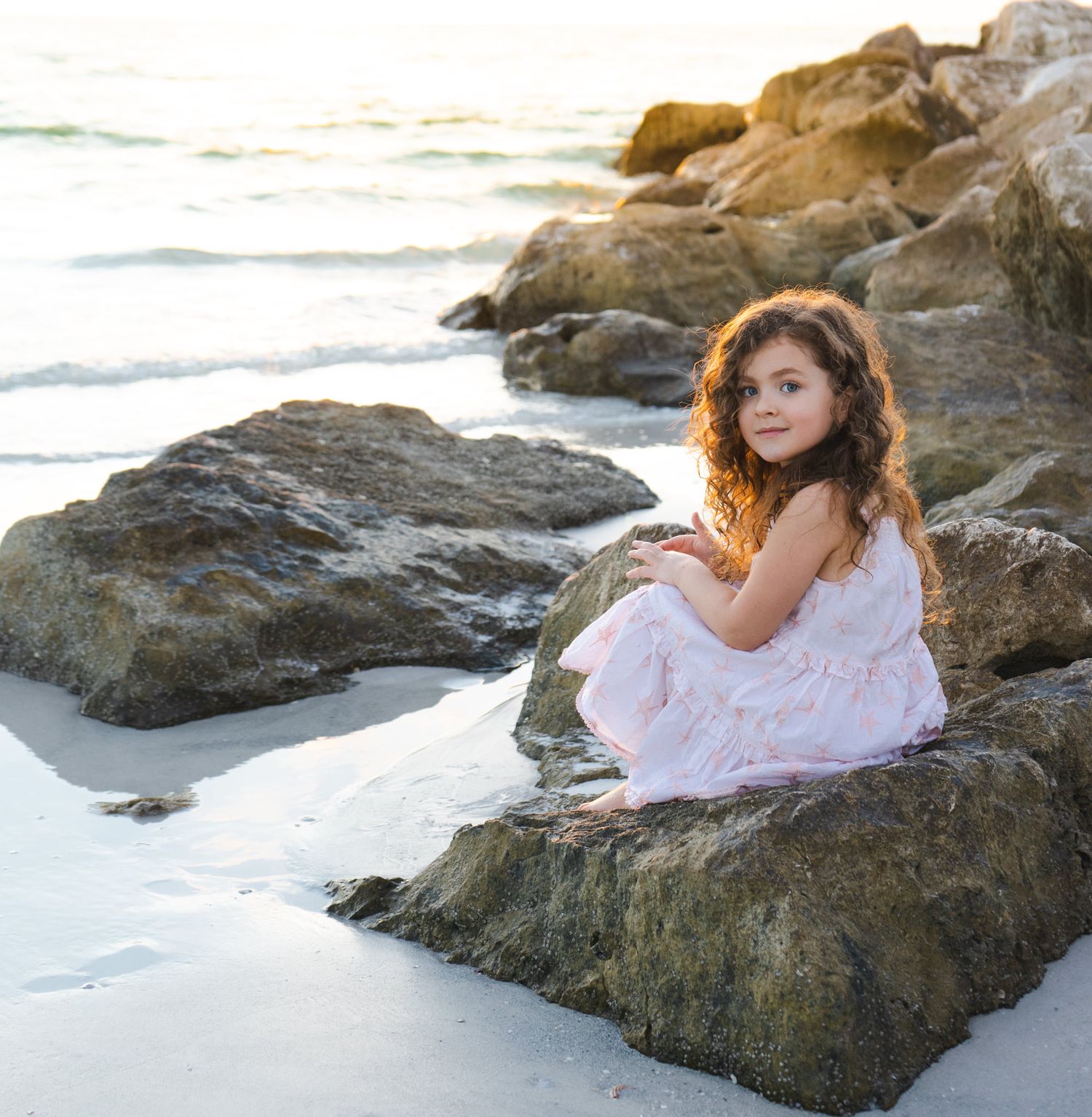 Family photo at sunset on Upham Beach in Pinellas County - little girl smiling on rocks