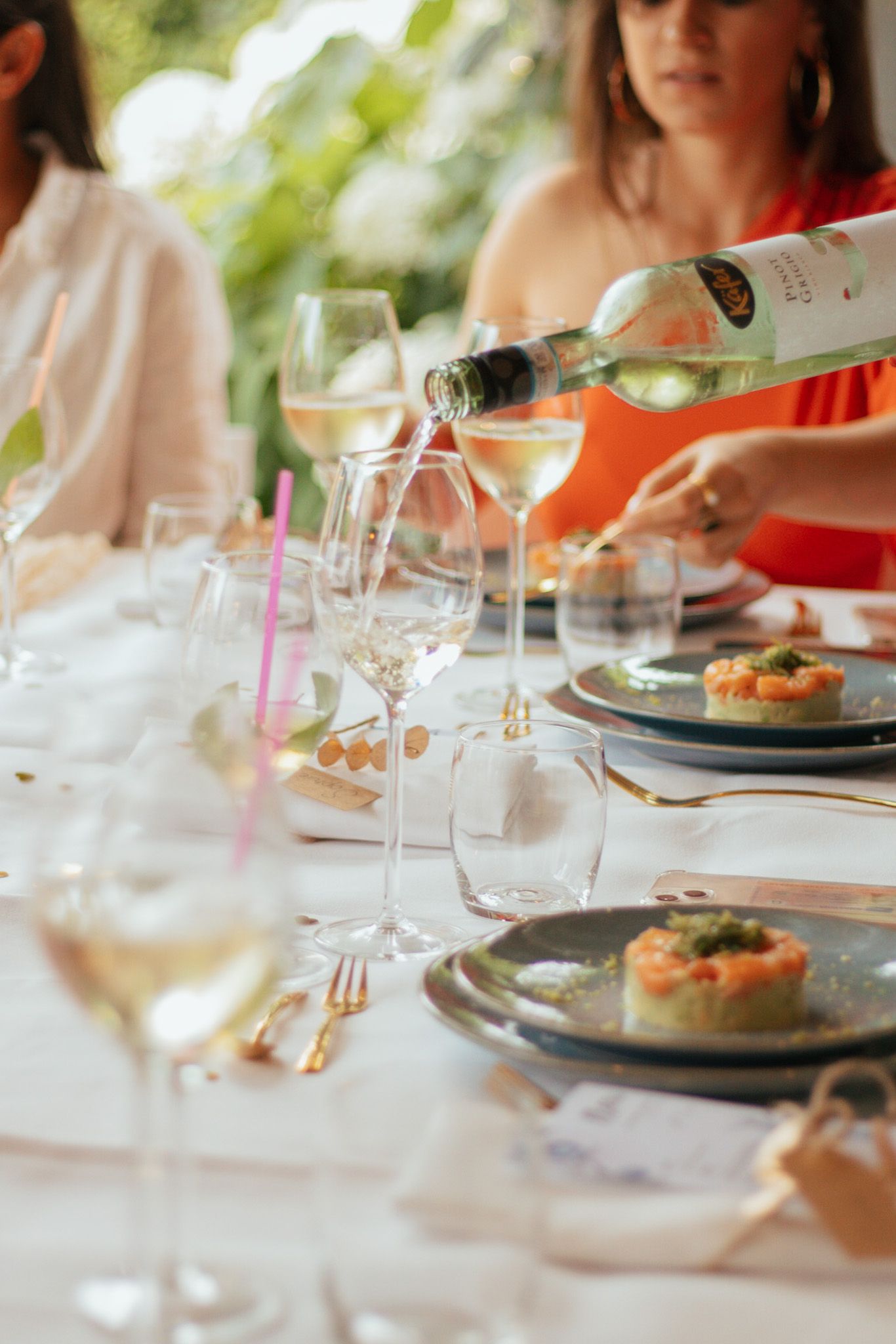 Gast schenkt wijn in tijdens een sfeervol diner aan een elegant gedekte tafel.