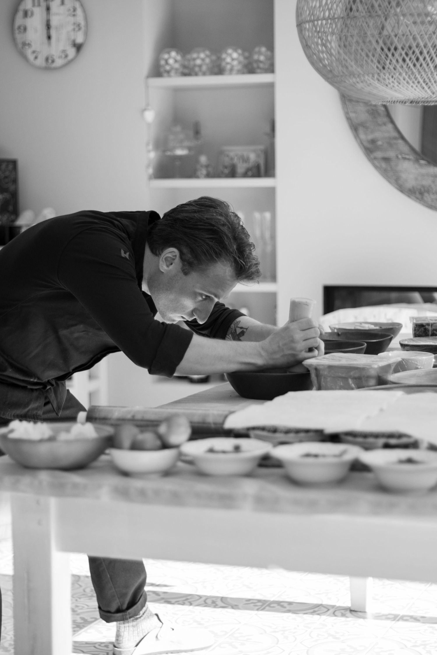 Zwart-wit foto van een chef-kok die zorgvuldig een bord opmaakt in een keuken.