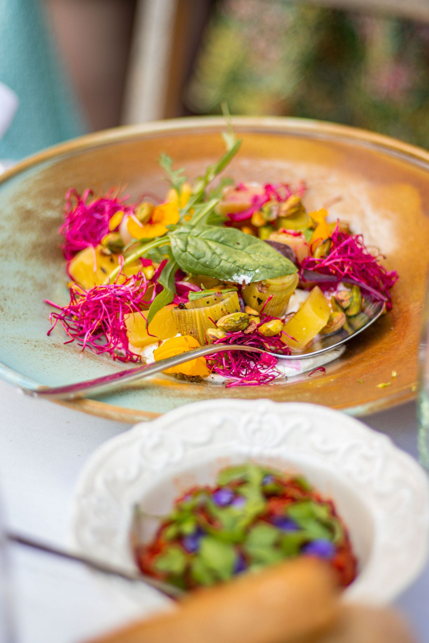 Kleurrijk gepresenteerd gerecht met eetbare bloemen en een bijgerecht op tafel.