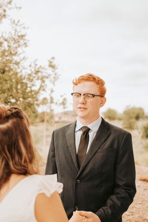 Profile view of formal couple during outdoor wedding ceremony.