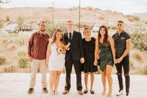Wedding party poses together outdoors in coordinated formal attire against desert landscape.
