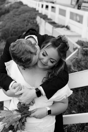 Black and white intimate moment between newlyweds on outdoor steps with floral bouquet.
