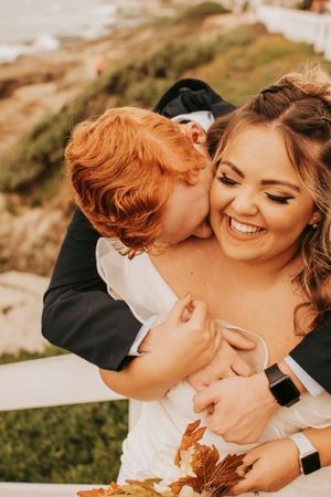 A romantic beach wedding photoshoot captures a joyful couple embracing in warm sunset light.