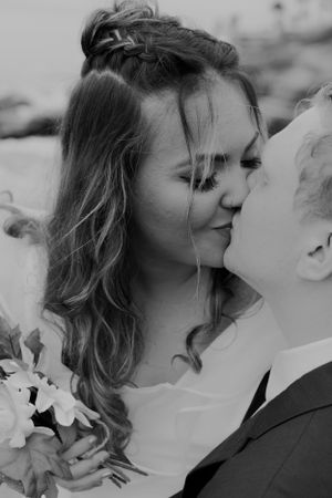 A black and white wedding photo captures an intimate moment between newlyweds.