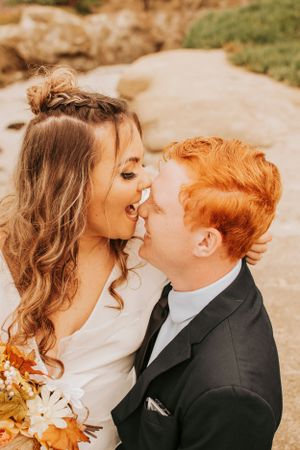 A joyful wedding moment captured as couple shares laughter against coastal backdrop.