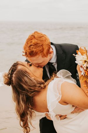 A romantic wedding portrait captures an intimate moment between newlyweds on the beach.