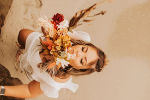 Artistic portrait with fall-colored dried flowers and a delicate white fabric creating a romantic mood.