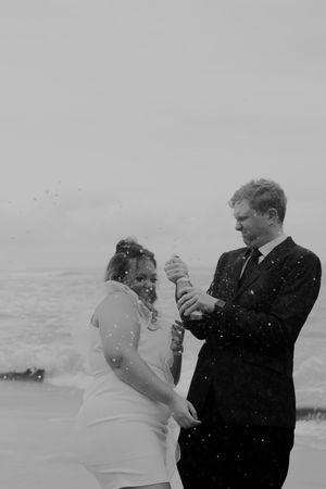 Romantic black and white beach scene of a couple sharing an intimate moment in the ocean spray.