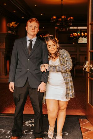 Elegant couple posing inside venue with warm lighting and decorative floor tiles.