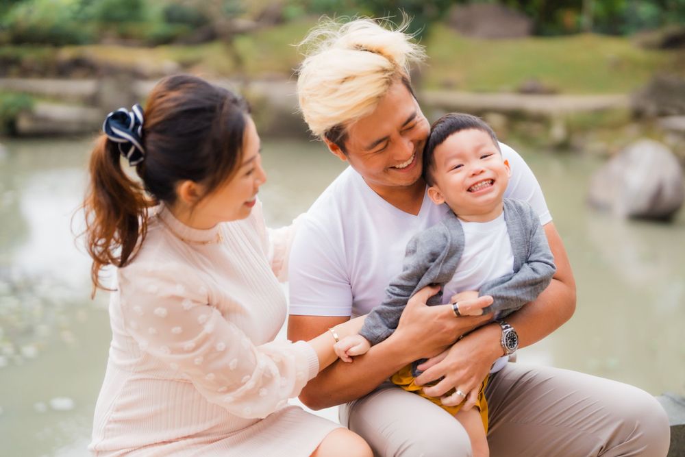 A joyful outdoor family moment shared by the pond on a sunny day.