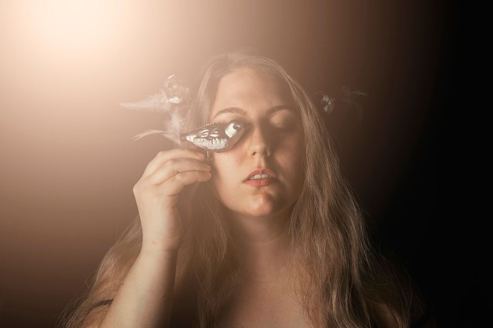 Dreamy portrait with butterfly decoration in warm ambient lighting.