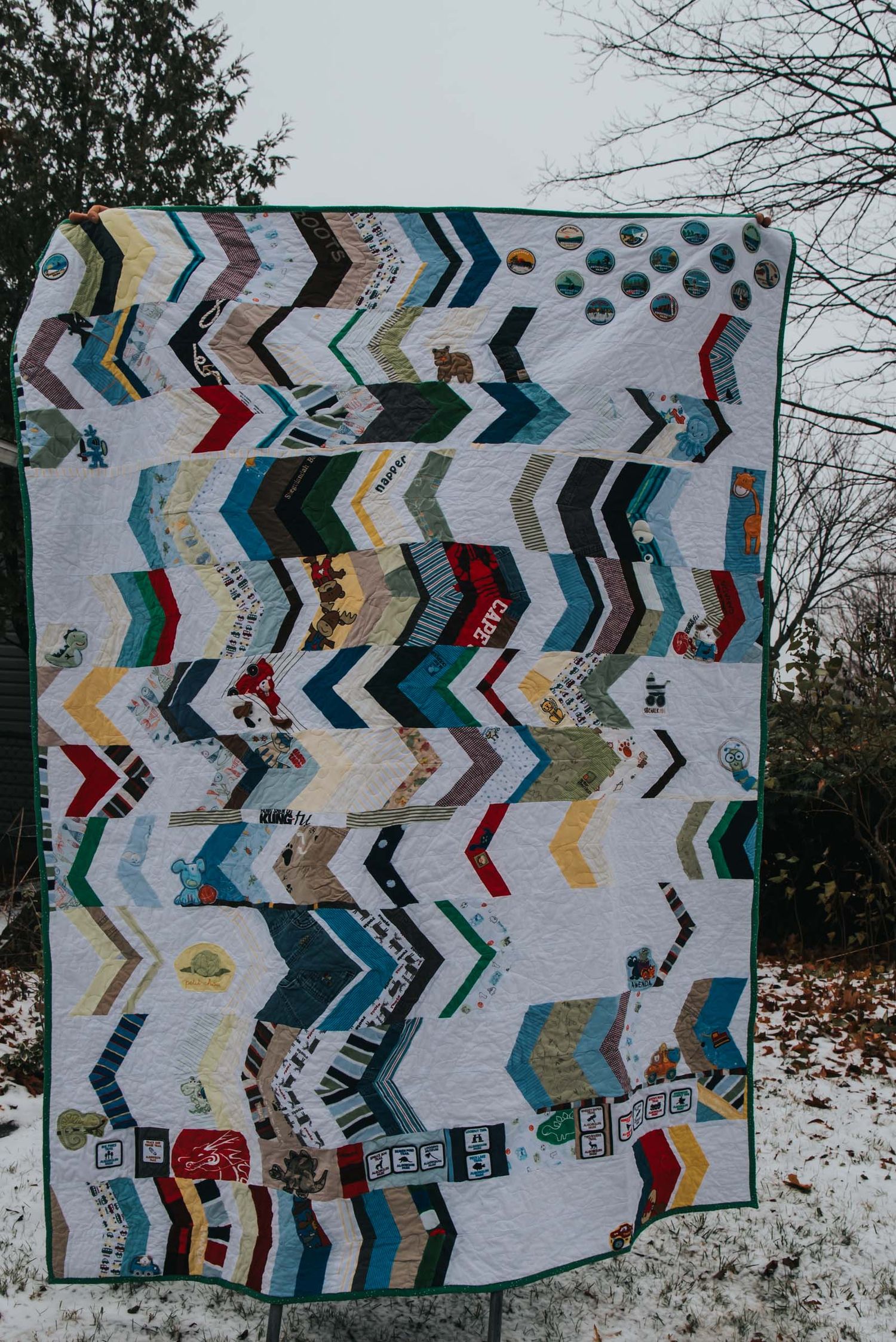 Horizontal herringbone memory quilt with white fabric between strips of clothing and patches.