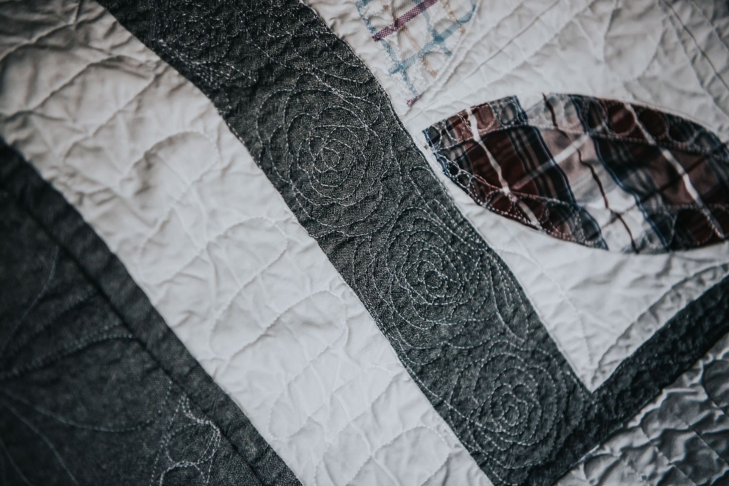 Free motion quilting of a flower pattern on a quilt with dark blue chambray fabric.