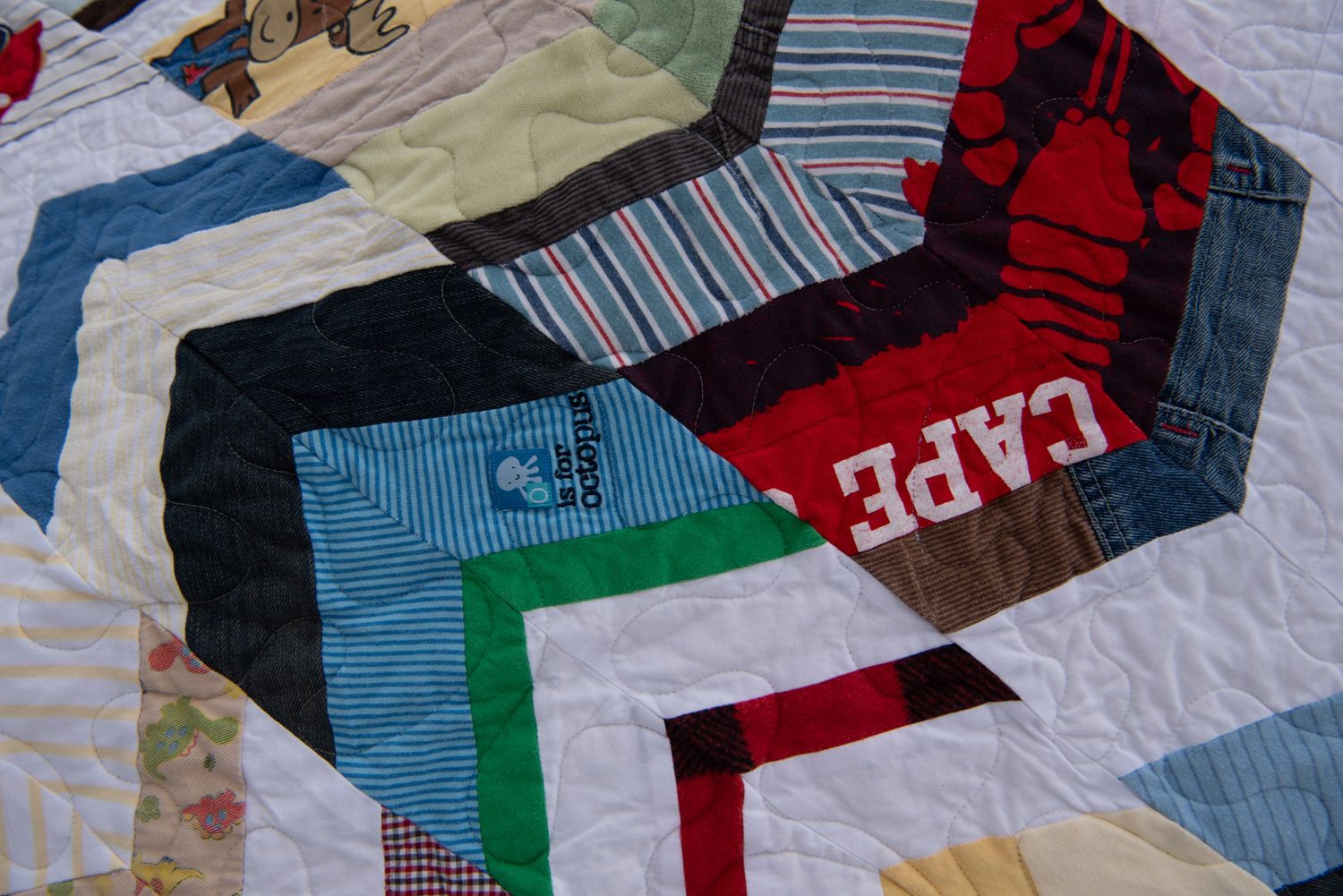 Angled image of a herringbone memory quilt made with baby clothes and white fabric.