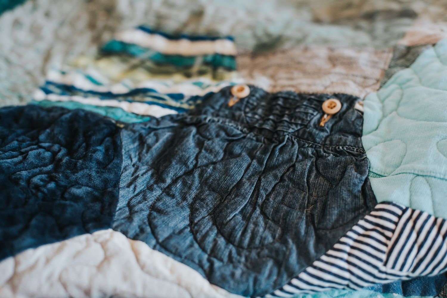 Beautiful, textured memory quilt showcasing a little pair of baby overalls.