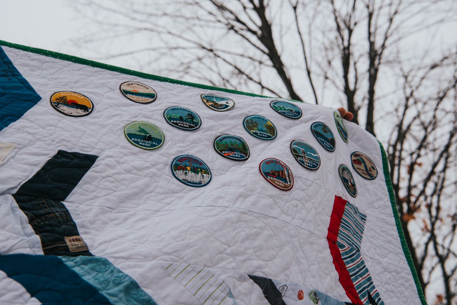 Provincial park patches are sewn into a herringbone memory quilt with white between the layers of clothing.