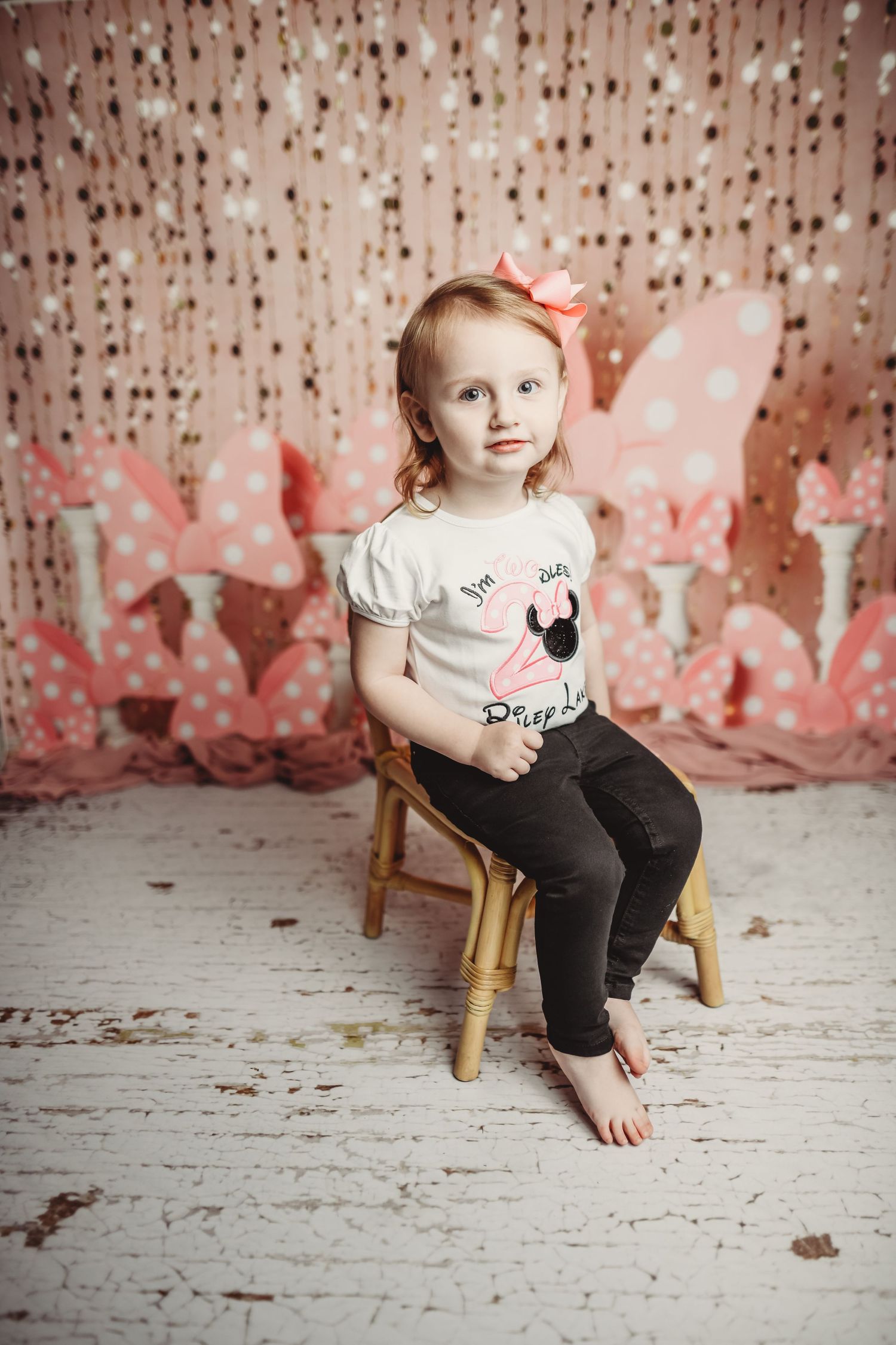 Small wooden chair against a distressed pink and white backdrop with sparkly decorative elements.