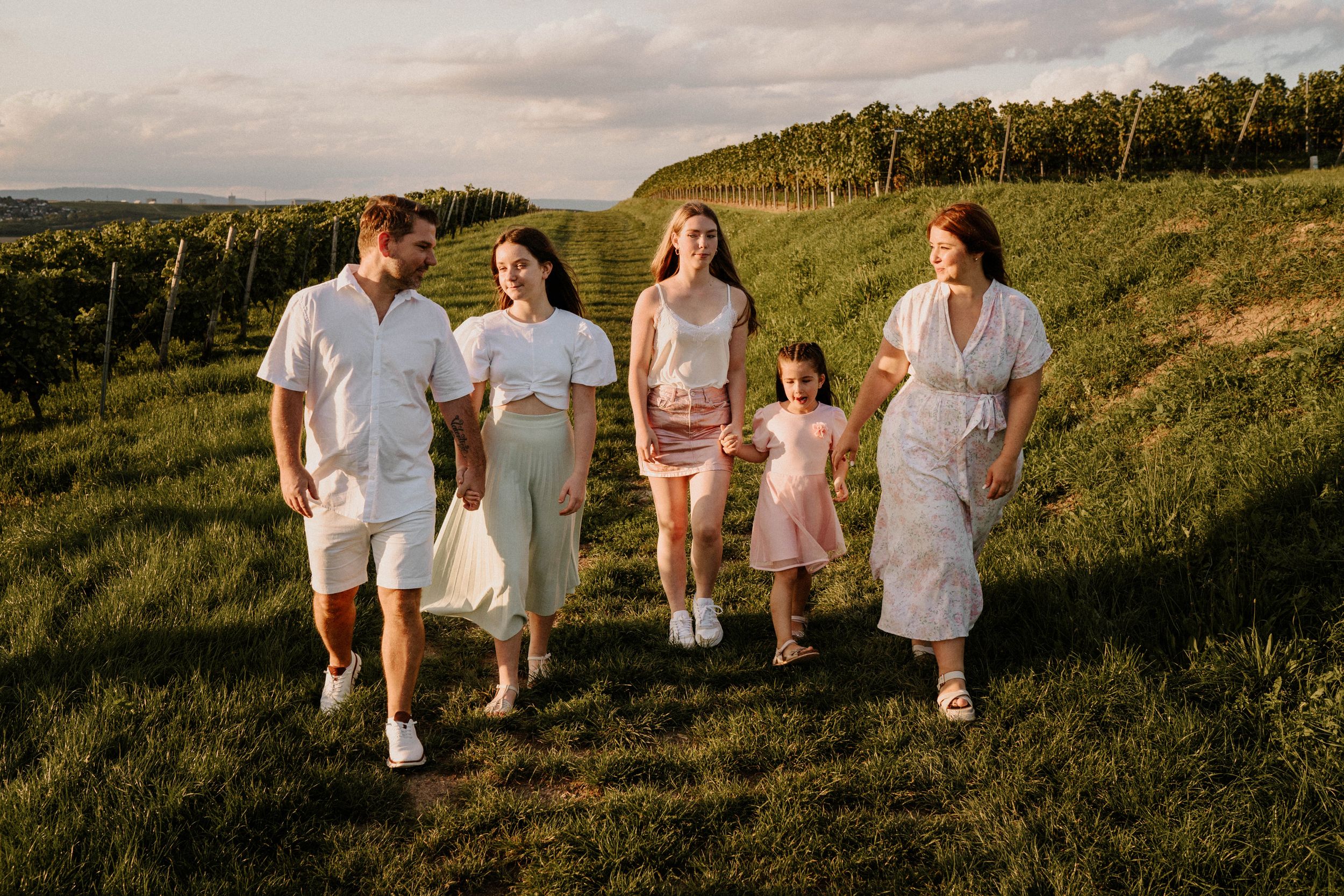 Group walking together across a hilltop meadow at sunset wearing coordinated outfits.
