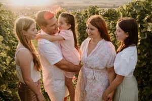 Candid family moment captured in golden sunlight on a grassy hillside.
