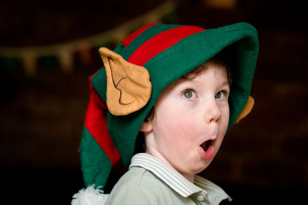 Young boy wearing a Christmas Elf hat, with expression of surprise and delight