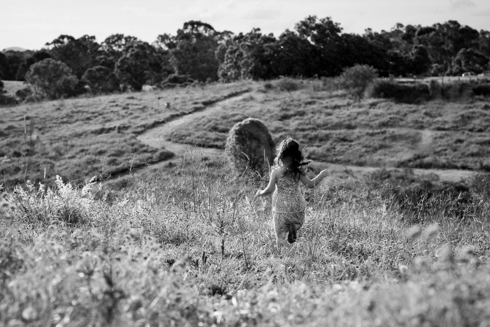 Child running through long grass, towards hills in the distance
