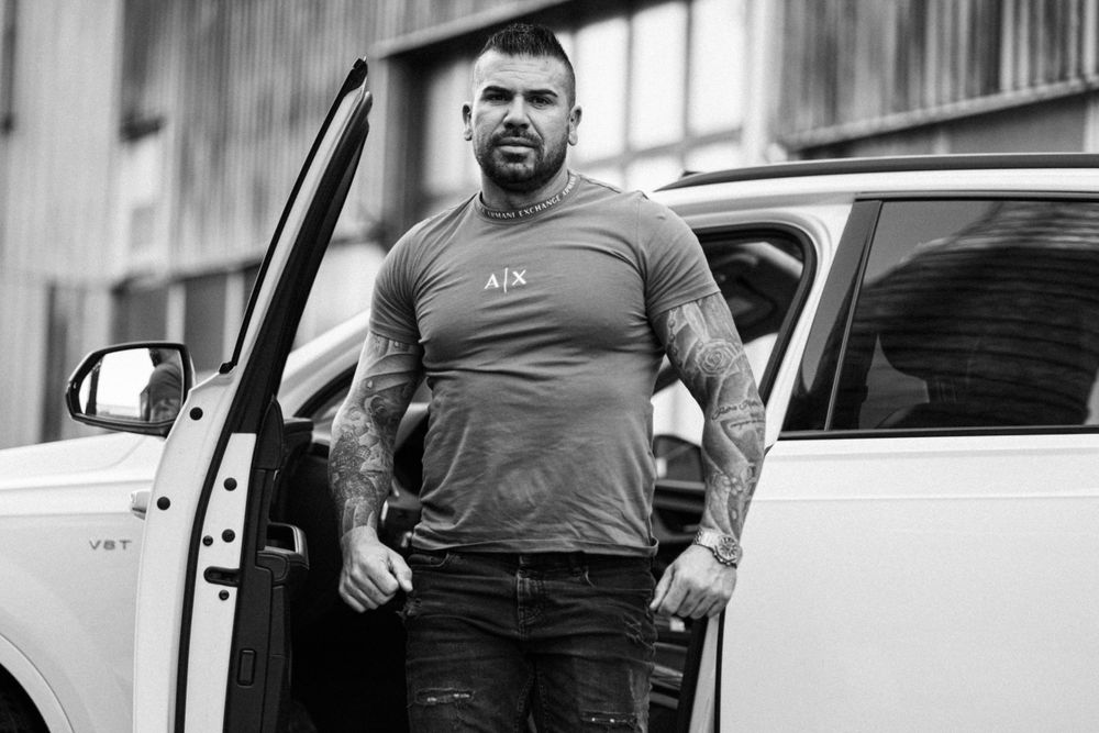 Person in grey shirt exiting white luxury vehicle in urban setting.