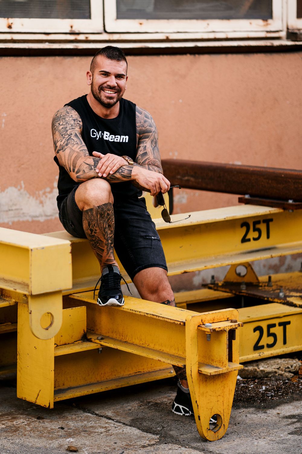 Person in black athletic wear sitting on yellow industrial equipment outdoors.