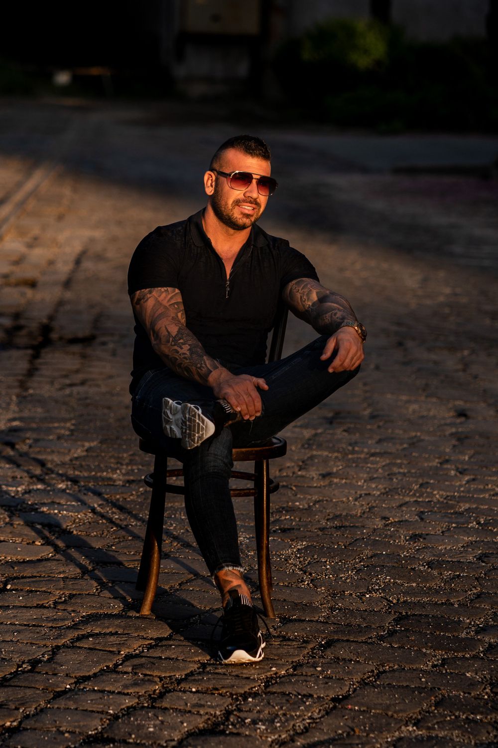 Athletic person in black outfit sitting on wooden chair during sunset.