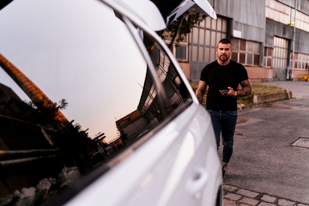 White luxury vehicle with reflection in urban industrial setting.