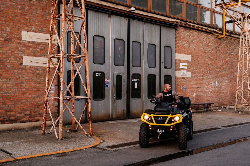Can-Am ATV positioned in front of large industrial garage doors with brick facade.