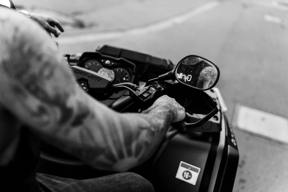Close-up black and white detail shot of motorcycle handlebars and controls.