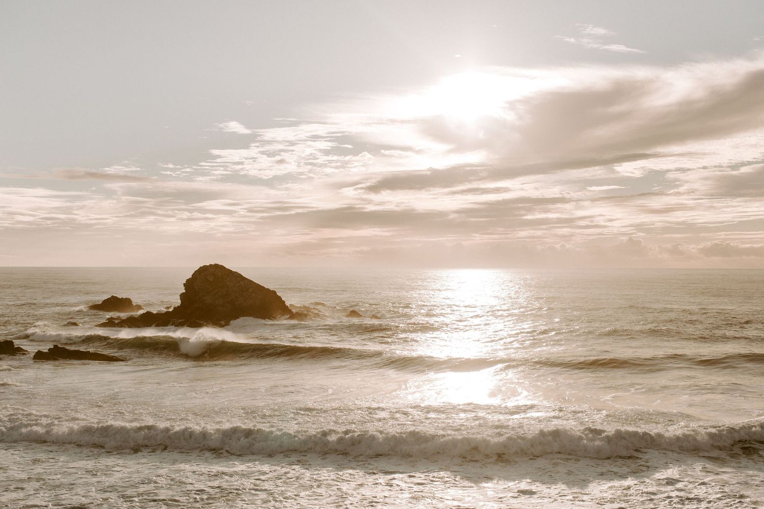 Peaceful seascape with rocky outcrop during golden hour sunset.