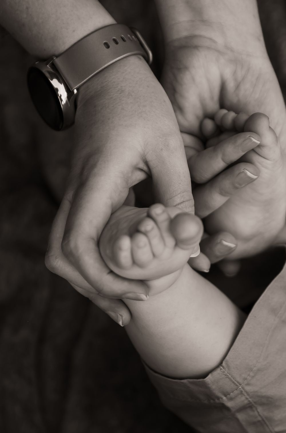 b&w parent child hands holding baby feet detail