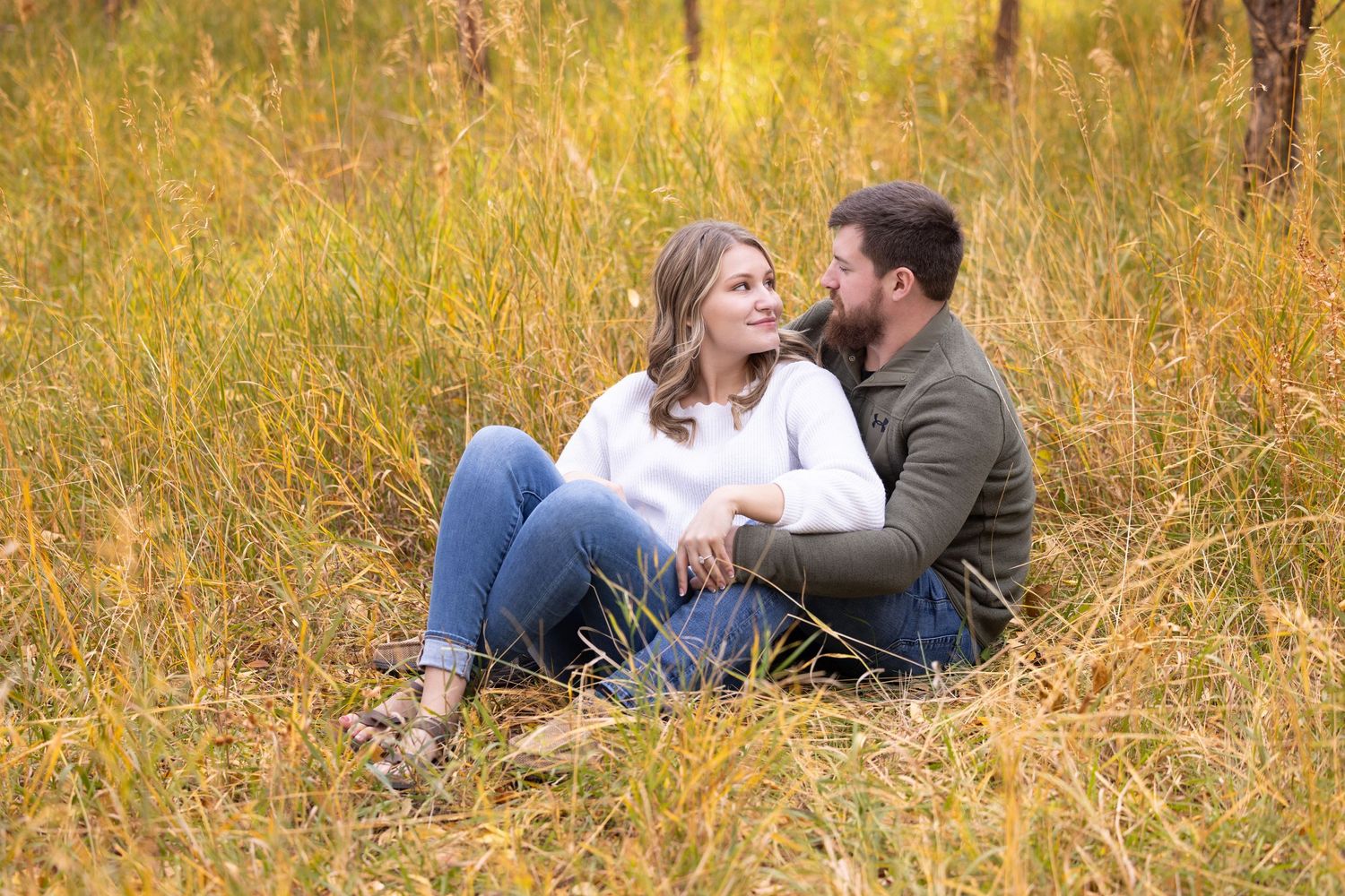 Couple sharing romantic moment while sitting in tall autumn grass.