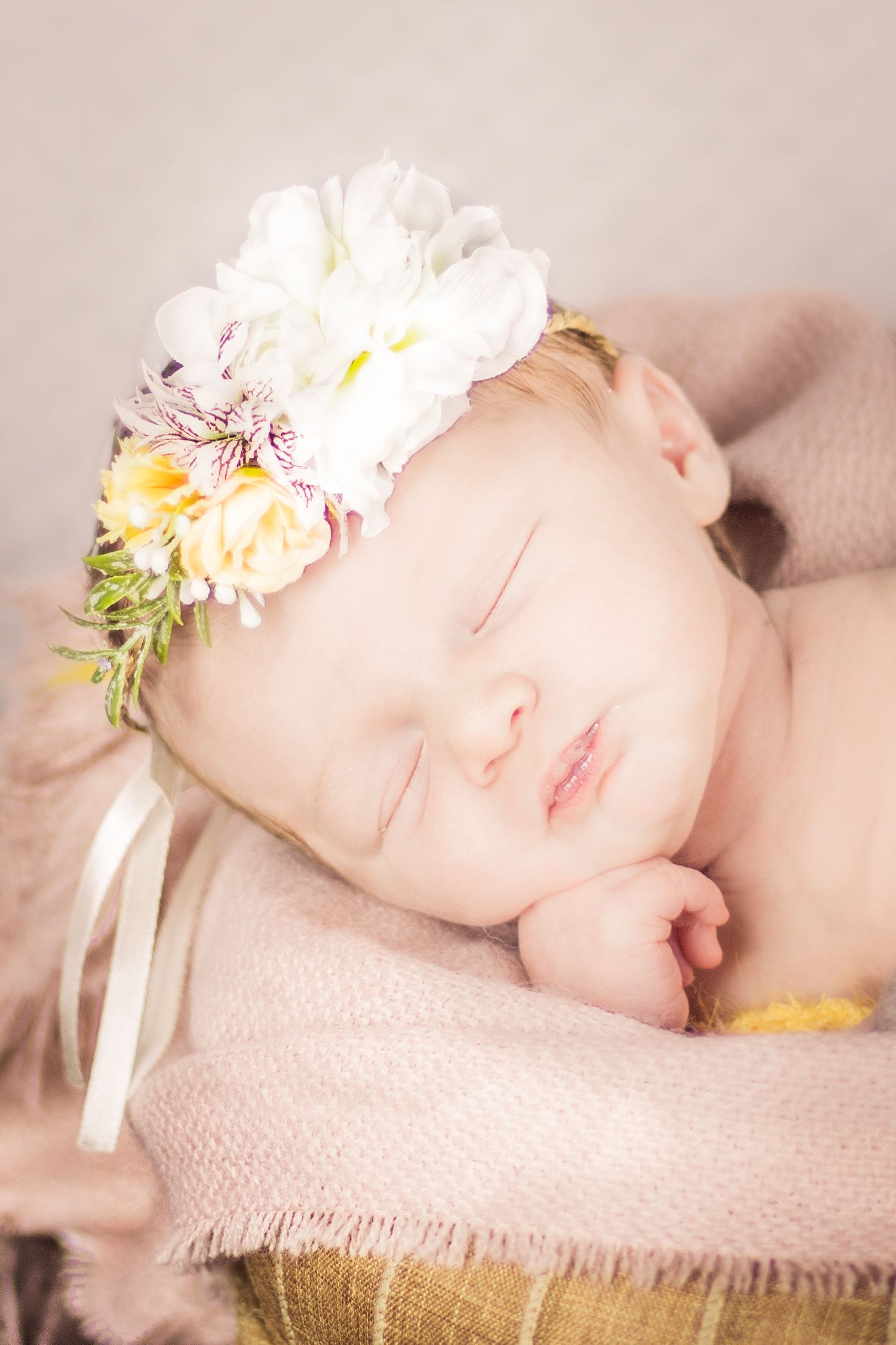 sleeping baby with flower headband propping head up on hands