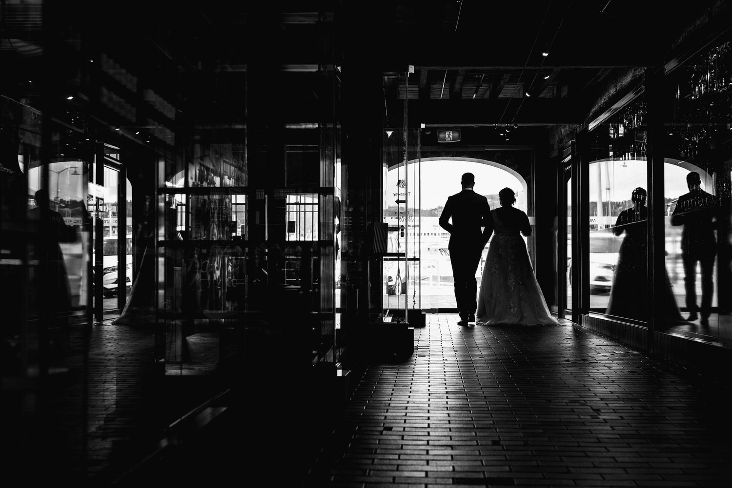 Silhouetted figures in a dark industrial hallway with dramatic backlighting.