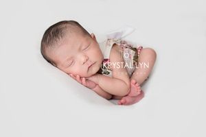 Small baby curled so cozy in cream and floral with white backdrop