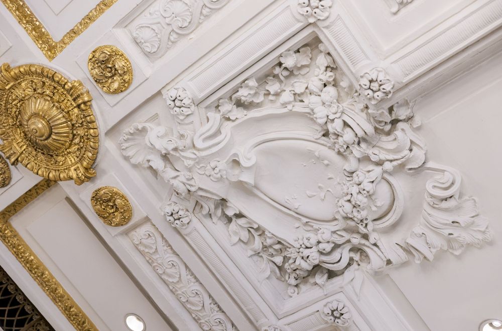 Detailed view of ornate white and gold ceiling molding with rococo designs.